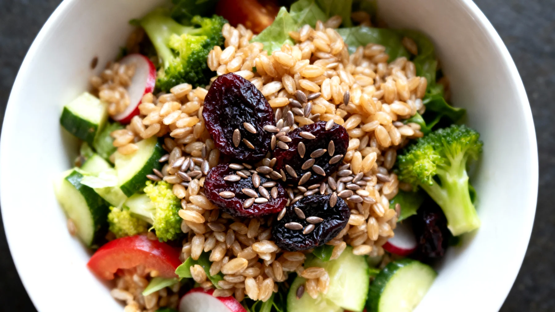Insalata di farro con prugne secche, semi di lino e verdure crude"